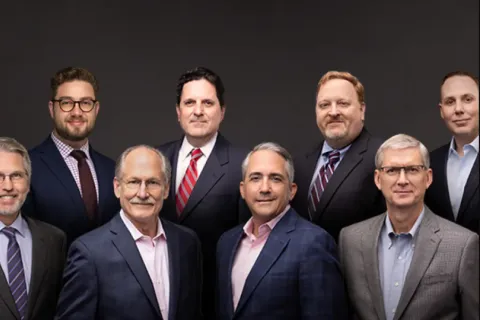 Group portrait of twelve diverse business professionals in formal attire against a dark background