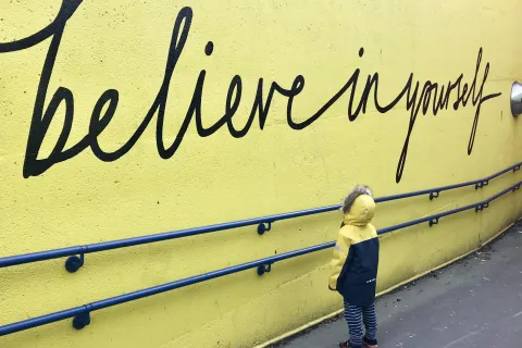 a child standing next to a wall with a sign on it
