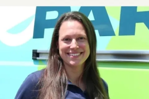 Portrait of Lizzie Sigafoos, a standout female franchise owner, smiling in front of a branded vehicle background.