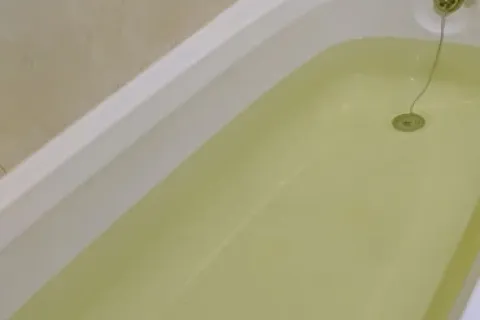 Close-up of a bathtub filled with clear water showing the drain and overflow plug chain.