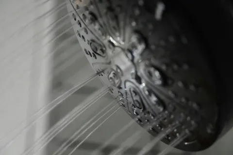 Close-up of a showerhead with multiple streams of water flowing downwards in a bathroom setting