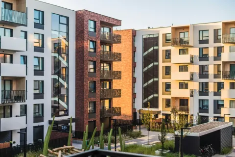 Modern apartment buildings with balconies surrounding a landscaped courtyard in soft evening light.