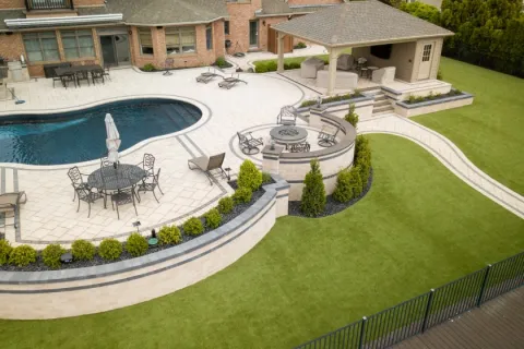 Luxury backyard with swimming pool, patio seating, fire pit area, and covered outdoor living space.