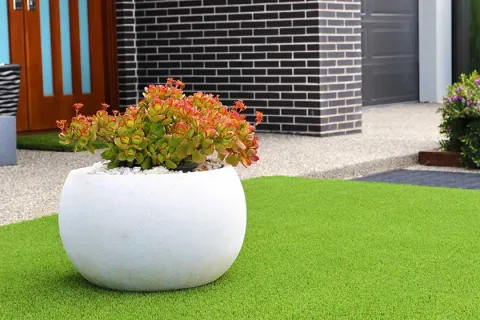 Modern white planter with colorful succulent plants on a green lawn in a stylish outdoor space.