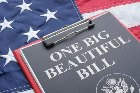 Clipboard with One Big Beautiful Bill text on American flag background symbolizing unity and legislation.