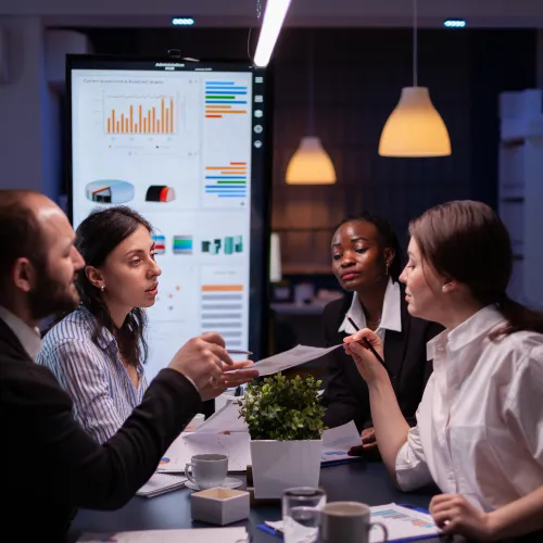 a group of people sitting at a table with a white board