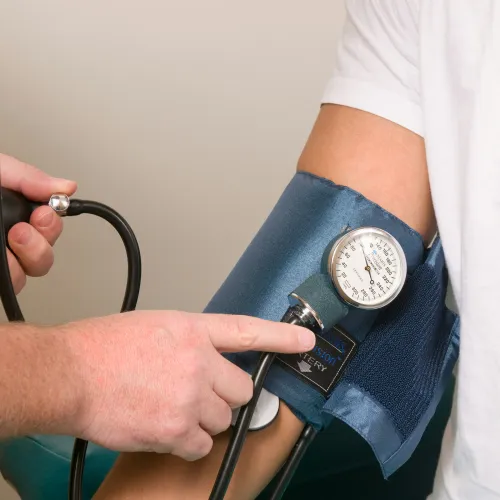 Healthcare professional measuring blood pressure on a patient's arm with a sphygmomanometer.
