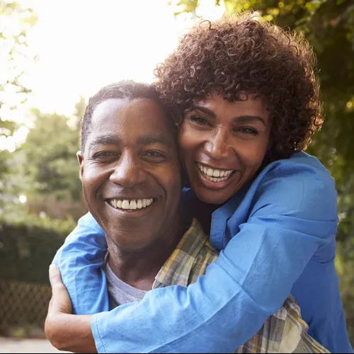 Happy couple embracing outdoors, smiling and enjoying quality time together in a natural setting.