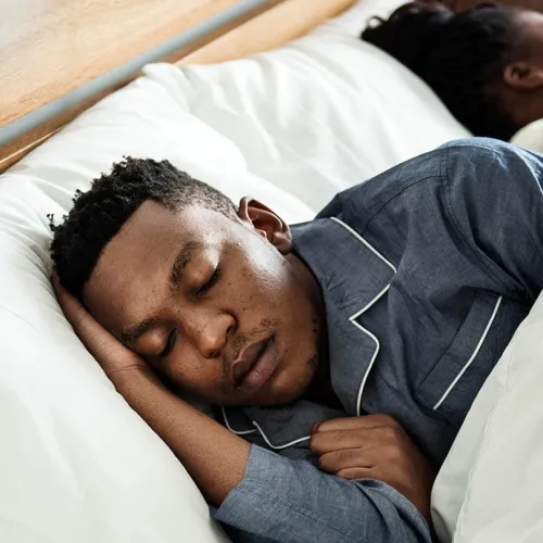 A peaceful man sleeping in bed, showcasing tranquility and cozy bedroom ambiance.