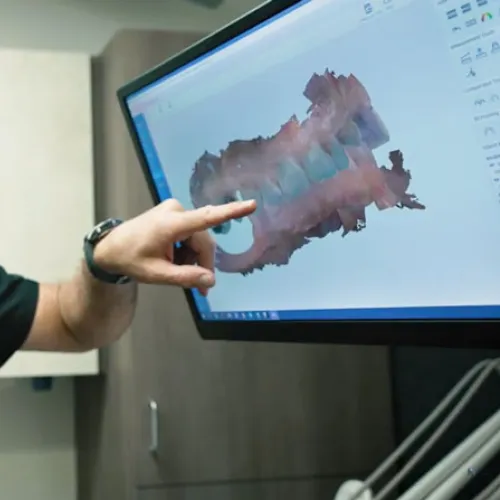 Older woman in red shirt smiling at receptionist across the counter in a professional office setting.