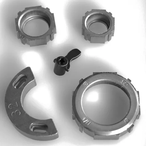 Metal lockring components and a small lever arranged on a white surface in grayscale.