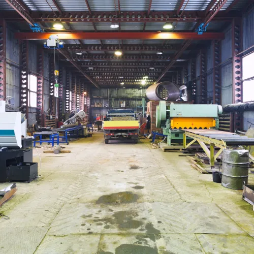 Inside view of a spacious industrial workshop with machinery and metalworking equipment along the sides