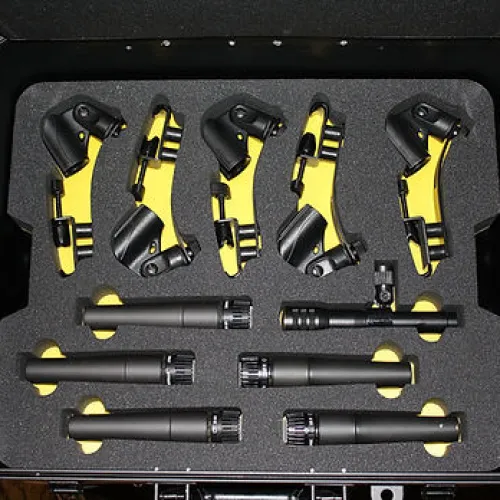 Set of black microphones and mounts organized in protective foam inside a hard carrying case.