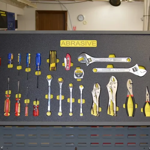 Organized wall-mounted tool board labeled Abrasive with hammers, screwdrivers, wrenches, pliers, and measuring tape