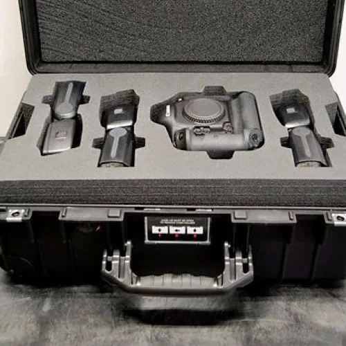 Protective hard case with custom foam inserts holding a camera body and multiple lens attachments.