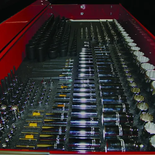 Organized tool drawer with various socket wrench sizes and extensions neatly arranged inside a red toolbox.