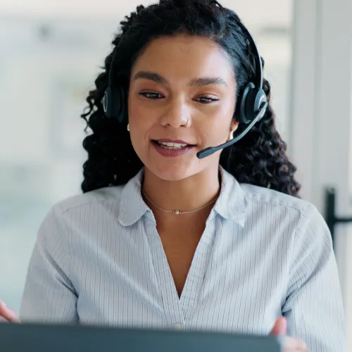 Customer service representative wearing headset engaging in video call at modern office desk