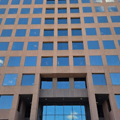 Modern office building with reflective glass windows and a symmetrical facade under a clear sky