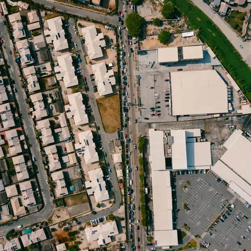Aerial view of residential neighborhood with rows of houses adjacent to commercial buildings and a green canal.
