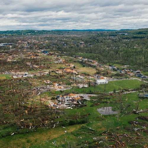 Aerial view of a residential area severely damaged by a tornado with debris and destroyed homes scattered wide.