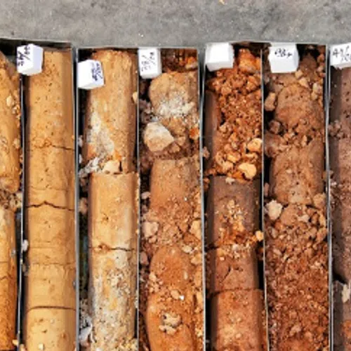 Vertical soil core samples in metal boxes showing layers of different soil types and textures for analysis.