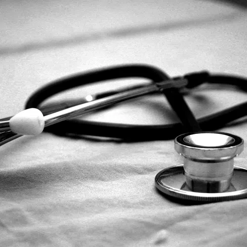 Close-up of a stethoscope lying on a fabric surface in black and white photography.