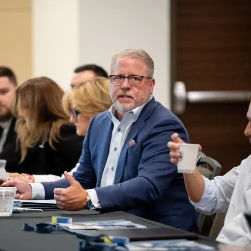 Business professionals engaged in discussion during a meeting at a conference table with documents and drinks.