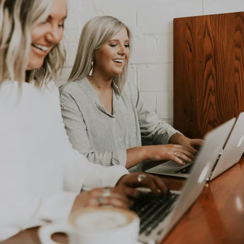 a couple of women looking at a laptop