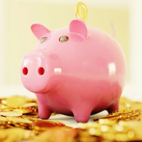 a pink piggy bank on a pile of gold coins