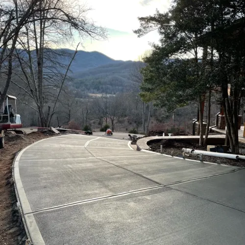a paved area with trees and mountains in the background