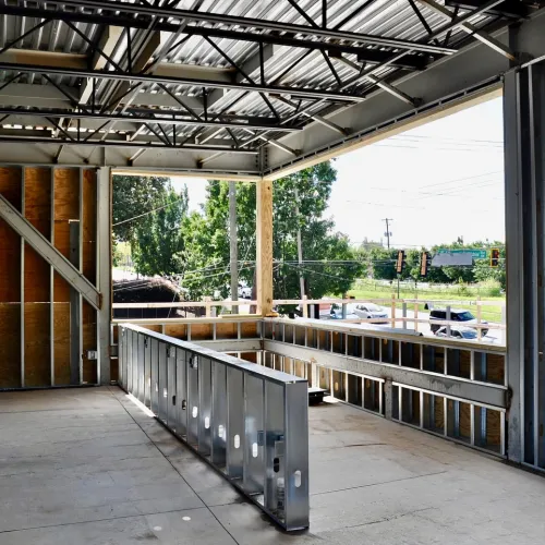Interior view of a commercial building under construction with exposed steel framing and concrete flooring.