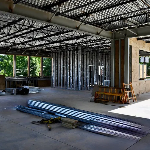 Interior of a partially constructed commercial building with metal framing and open ceiling beams.