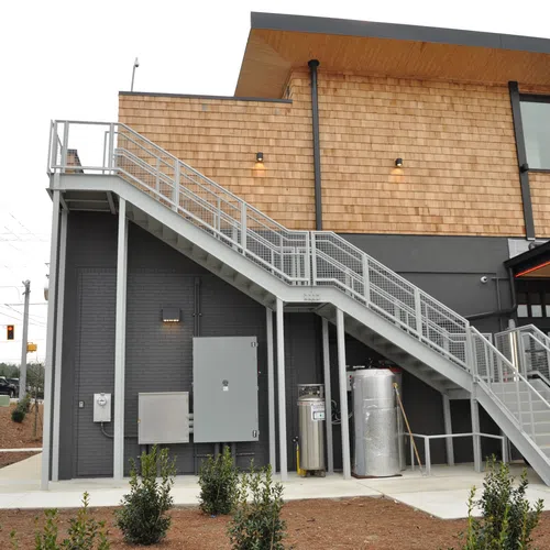 Modern commercial building with exterior metal staircase leading to second floor under natural daylight