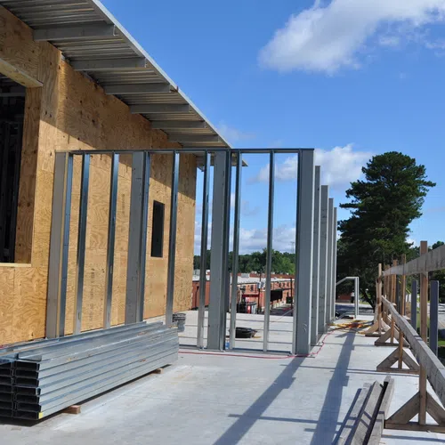 Commercial building under construction with metal framing and plywood sheathing on a clear sunny day.