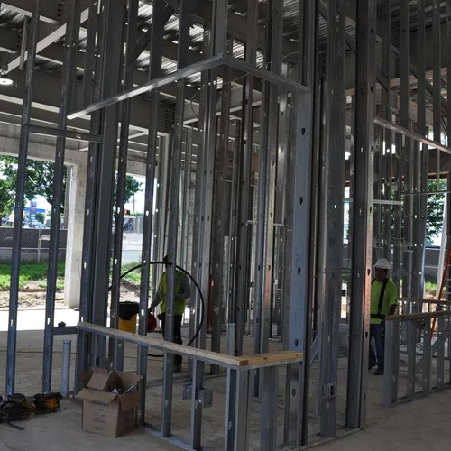 Construction workers installing metal framing inside a building under construction with tools and materials around.