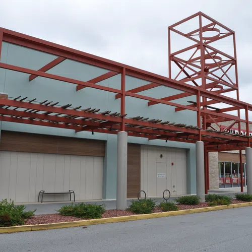 Empty storefront with red steel awning and pillars in a shopping center on a cloudy day