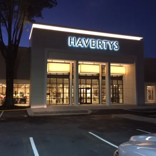 Havertys furniture store exterior at night with illuminated signage and empty parking spaces.