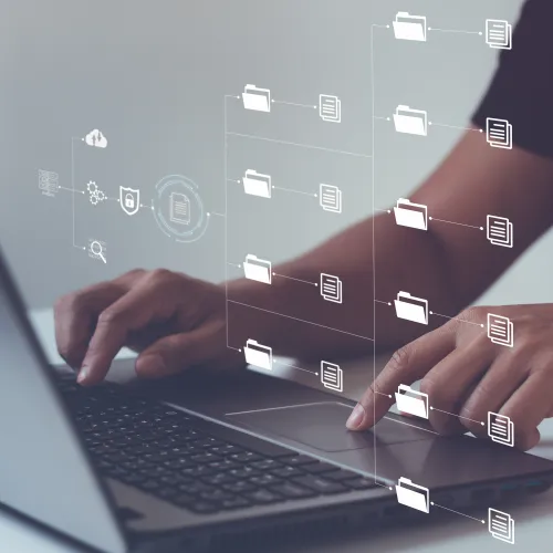 Person using laptop with digital file and folder icons representing data management and cloud storage.