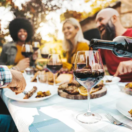 a group of people sitting at a table with food and wine