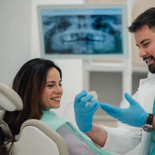 Dentist explaining dental treatment to smiling female patient with dental x-ray in background