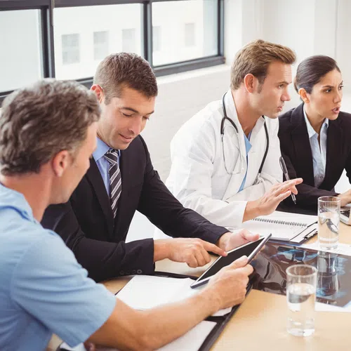 a group of people sitting around a table looking at a laptop