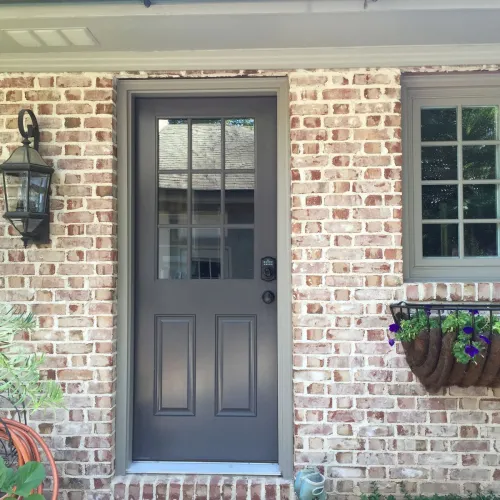 the grey front door of a brick building