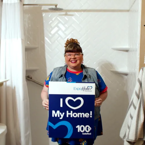 a woman holding a 100% satisfied sign in front of her new shower
