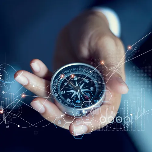 Hand holding a compass overlaid with digital graphs and charts representing business strategy and direction.