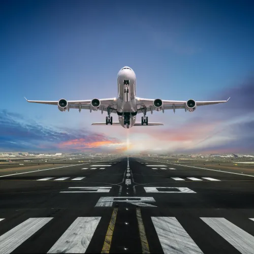 Large commercial airplane taking off from runway at sunset with clear sky in the background
