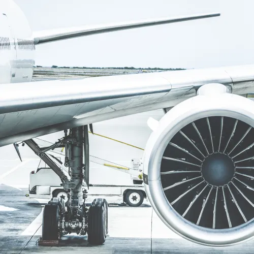 Close-up of airplane engine and landing gear on the tarmac at an airport under daylight conditions