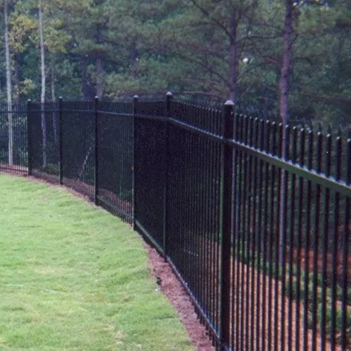 a black fence with a green lawn and trees in the background