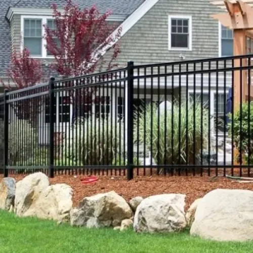 a fenced in yard with a house and trees in the background