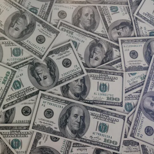Pile of US one hundred dollar bills scattered displaying Benjamin Franklin's portrait