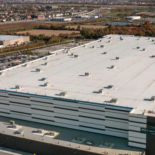 Aerial view of a large distribution center with expansive parking and multiple loading docks on a sunny day.